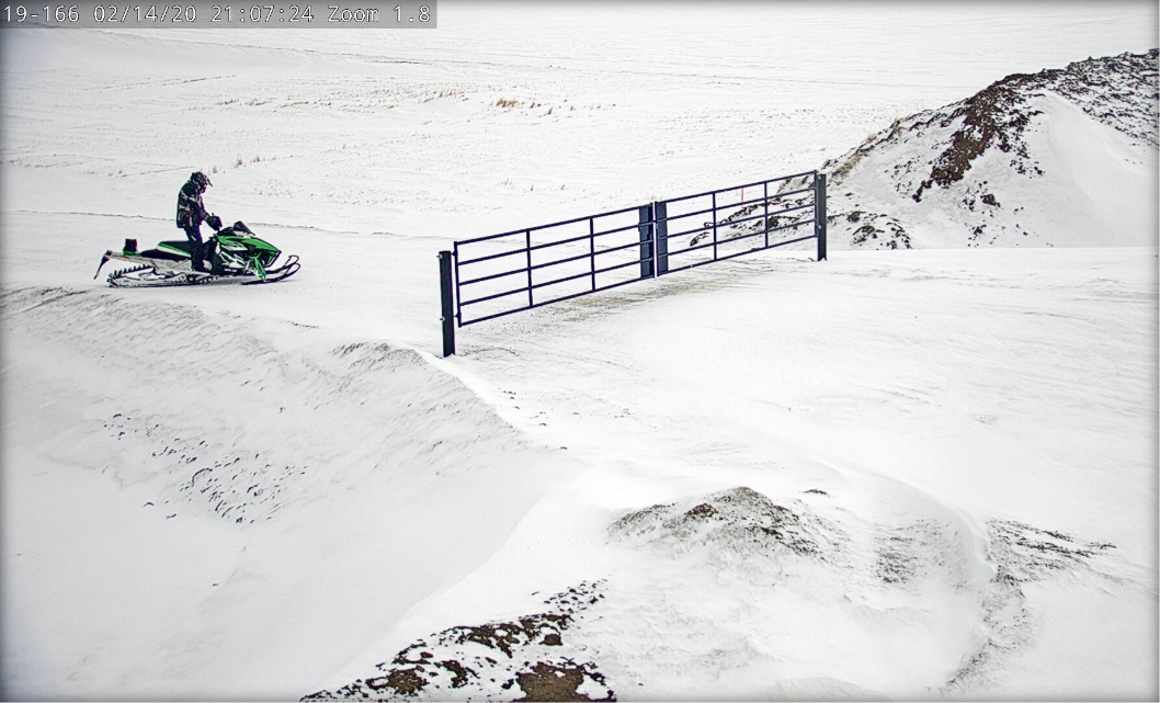 A man riding on a green snowmobile caught on camera at one of the site served with Whitetail rental's Camera Monitoring Solutions