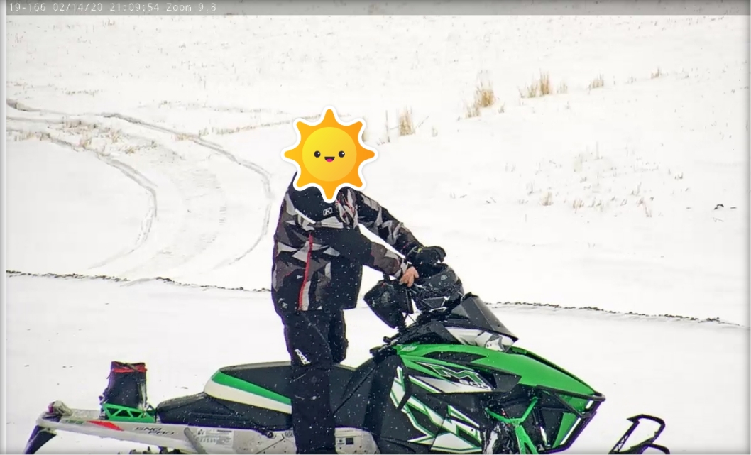 Image of a man riding a green snowmobile